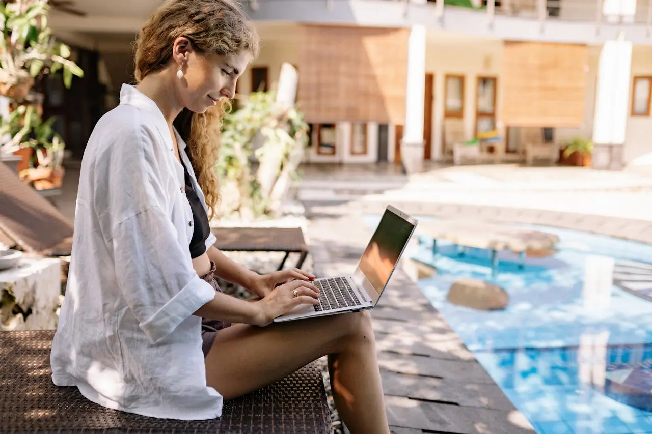 a woman by the pool on her laptop doing remote work